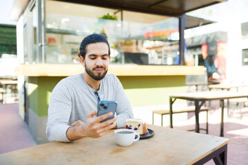 Happy man at the cafe restaurant texting on his phone