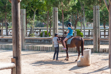 A young woman is learning how to ride a horse
