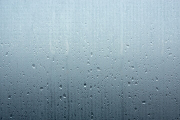 Foggy opaque glass with many small and large drops of water. The upper part is lighter than the...