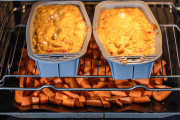 Polenta loafs in forms baking in the oven with roasted carrots.