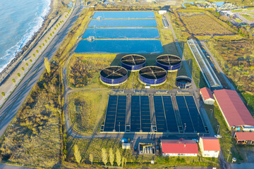 Aerial view of sewage treatment plant. Industrial water treatment with round water tanks for sewage recycling from drone view. Waste water management