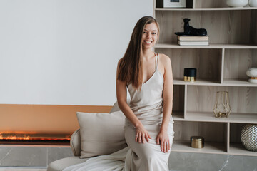 Elegant woman in a chic dress sitting gracefully in a modern living room, exuding sophistication...