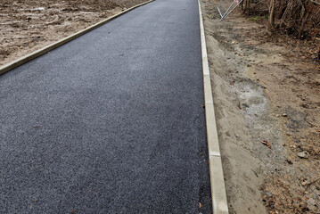 Fototapeta premium installation of concrete curb into concrete. in the space of the road, which so far has only a concrete base before laying the asphalt layer and rolling. mason, masonry, technology, slanted edge