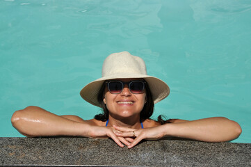 jovem mulher sorridente com chapéu em água de piscina, férias de verão 