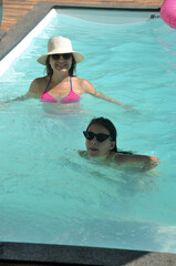 mãe e filha felizes brincando em area de piscina, férias de verão, alegria e lazer em piscina 