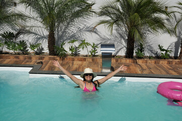 beldade sorridente e feliz de biquine rosa em area de piscina com paisagismo tropical , férias de...