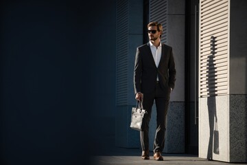 Elegant handsome man in classic suit standing near the office building. - obrazy, fototapety, plakaty