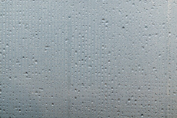 A foggy sheet of transparent plastic with a mesh structure. Water drops are arranged in lines. Close-up. Background. Texture.