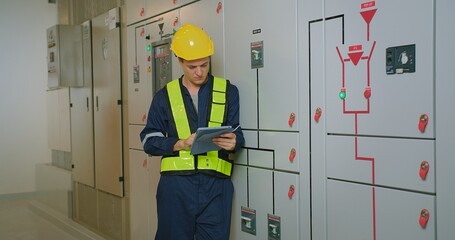 electricians electrical engineer in protective uniform wearing hard hat checking voltage control...