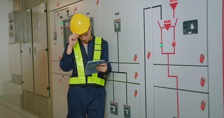 electricians electrical engineer in protective uniform wearing hard hat checking voltage control...