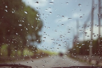 Cristal de coche con gotas de lluvia y paisaje desenfocado