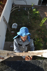 pintor trabalhador fazendo pintura de sobrado alto com escada 