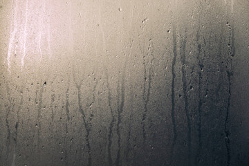 Foggy glass with drops and streaks of water. There are brightly sunlit and dark areas of the...