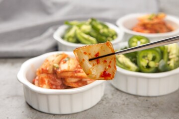 Showing a piece of kimchi in chopsticks.