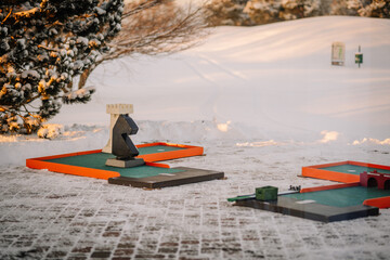 Riga, Latvia - December 6, 2023 -  snow-covered mini-golf course with colorful obstacles and a...