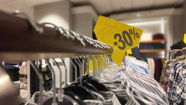 Sales signs in store, shopping discount sign on clothing rack, with designer shirts