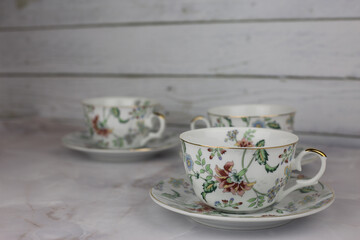 Obraz na płótnie Canvas Tea set with cups and saucers made of porcelain with a pattern of flowers stand on a white table