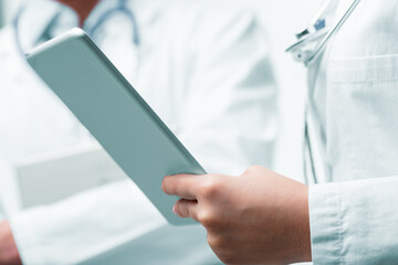 Medical professional's hands hold tablet, symbolizing innovation