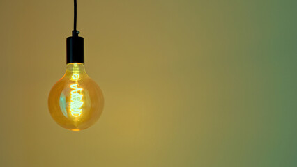 Retro Edison lamp on a yellow-green background. Space for text. Copyspace.