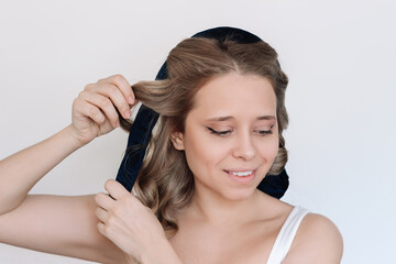 Heatless curl. A young attractive caucasian blonde woman removing soft curler from the hair...