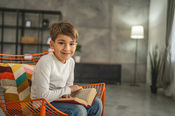 One boy caucasian child seven years old kid in room at home read book