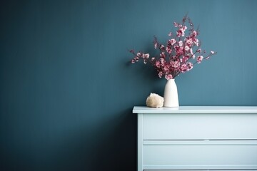 Blue wall with pink flowers in vase on dresser