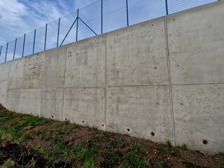 long straight supporting wall of cast cement mixer formwork. behind wall is soil that is brought...