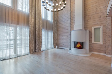 The living room is made of light wood with a high ceiling and large windows. Fireplace in .the...