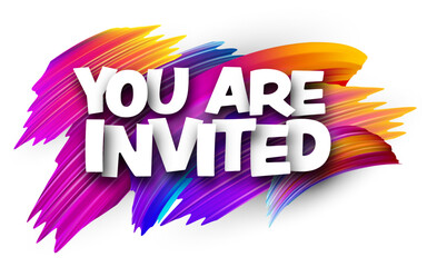 You are invited paper word sign with colorful spectrum paint brush strokes over white.