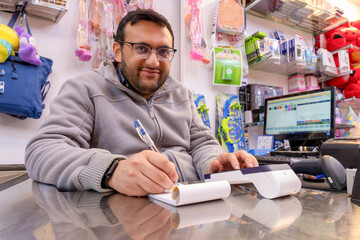 Shop owner writes down tax invoice for the customer needs to be used in reimbursement on the cashier table