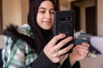 Fototapeta na wymiar muslim woman wearing hijab paying online through mobile phone application