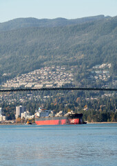 A ship passing under the Lions Gate Bridge that connects Downtown Vancouver with the North Shore as seen from Stanley Park during a fall season in Vancouver, British Columbia, Canada