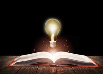 Glowing light bulb lamp over a book