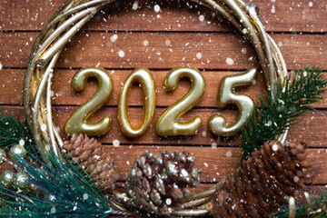 Happy New Year golden numbers 2025 on cozy festive brown wooden background with sequins, snow,...