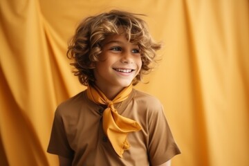 portrait of happy little boy with curly hair on yellow cloth background