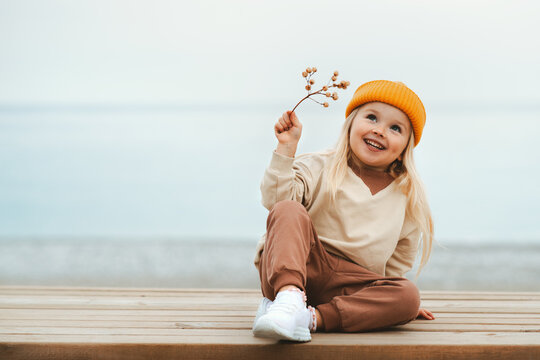 Child girl happy smiling outdoor walking on the beach kid 4 years old in yellow hat family travel vacations autumn season