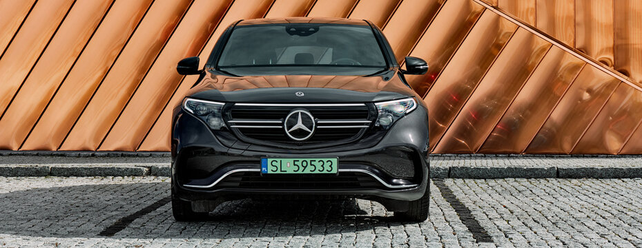 Front of electric Mercedes EQC standing against the golden wall of the Fire Museum. Range (WLTP) 414 km. Zory, Poland-10.06.2020