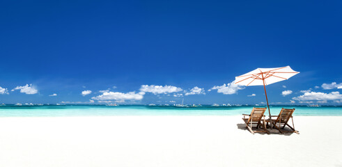 Sun umbrellas and wooden beds on tropical beach. Caribbean vacation on tropical shore