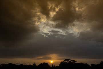 Sunset in the countryside with dramatic clouds and silhouettes of trees