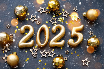 The golden figures 2025 made of candles on a black stone slate background are decorated with a...