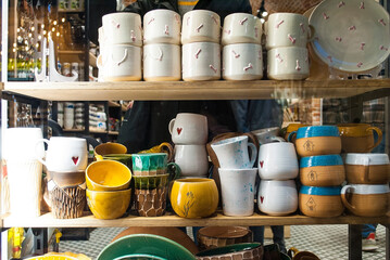 Bright multi-colored ceramic dishes in a store window. Cups of various shapes are neatly arranged...