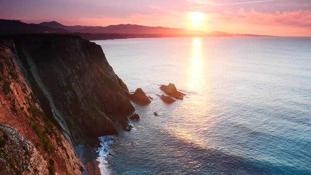 Sunset over rocky cliffs at Asturias coast in north Spain. View from Faro de Cabo Busto. Tourist attraction, place to visit.
