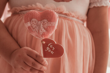 Little girl holding a heart-shaped lollipop in one hand