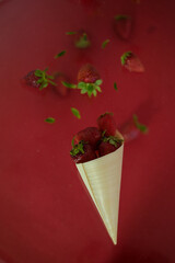 Strawberry levitating on a red background. A bowl of falling strawberries