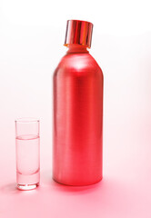 Aluminum bottle and a glass of vodka in pink light