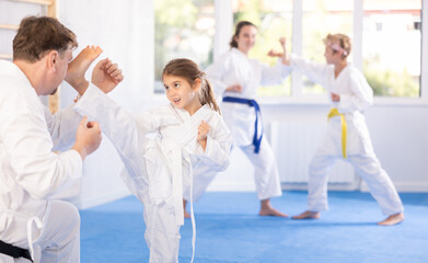 Parent with child partners during martial arts karate class train to perform basic blows to...