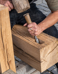 a man carves wood with a chisel