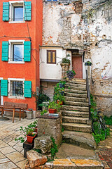 Fototapeta na wymiar old steps in a courtyard with fresh homemade flowers in pots in Croatia