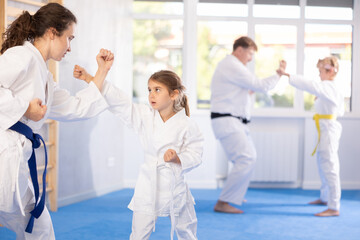 Mom trains little daughter to do kicks at karate lessons