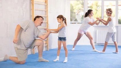 Fototapeten Parent and child train and perform basic punches and creases during self-defense lesson. Parent coach in teaches child effective protection during wrestling and dueling, martial arts. © JackF